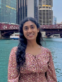 Divya wearing a floral blouse, standing in front of the Chicago River.