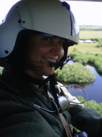 Helena smiling in a helicopter flying over a marsh.