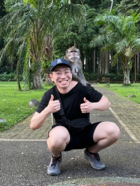 Jason smiling with his thumbs up while a monkey rests on his shoudlers.