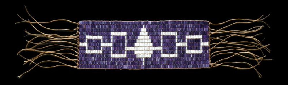 A photograph showing the symbols used to represent the 5 tribes of the Iroquois Confederacy on a woven belt. From left to right: The Seneca (white outlined square), the Cayuga (white outlined rectangle), the Onondaga (white arrow shape), the Oneida (white outlined rectangle), and the Mohawk (white outlined square). The symbols are connected by white horizontal lines.