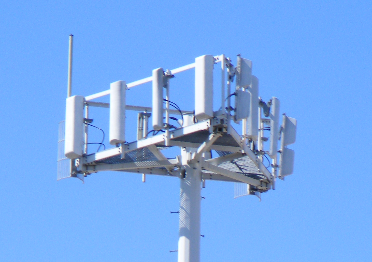 La parte superior de una torre celular, una estructura triangular con antenas.