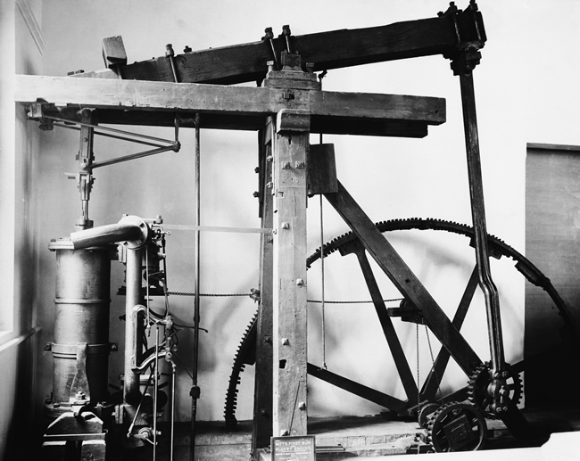 Low view of mechanic showing process of petroleum extraction and pointing  finger up to working oil pump to little boy. Adult oil worker introducing  child to his job. Oil industry concept. Photos