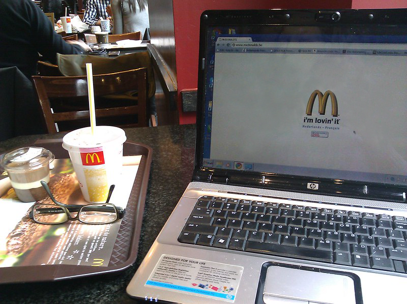 Hình ảnh một chiếc máy tính xách tay bên cạnh khay thức ăn và nước uống của nhà hàng McDonald.